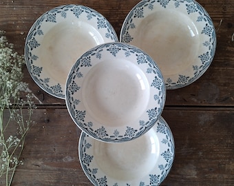 May include: Four white ceramic plates with blue floral designs. The plates are stacked on top of each other, with the largest plate on the bottom and the smallest plate on top.