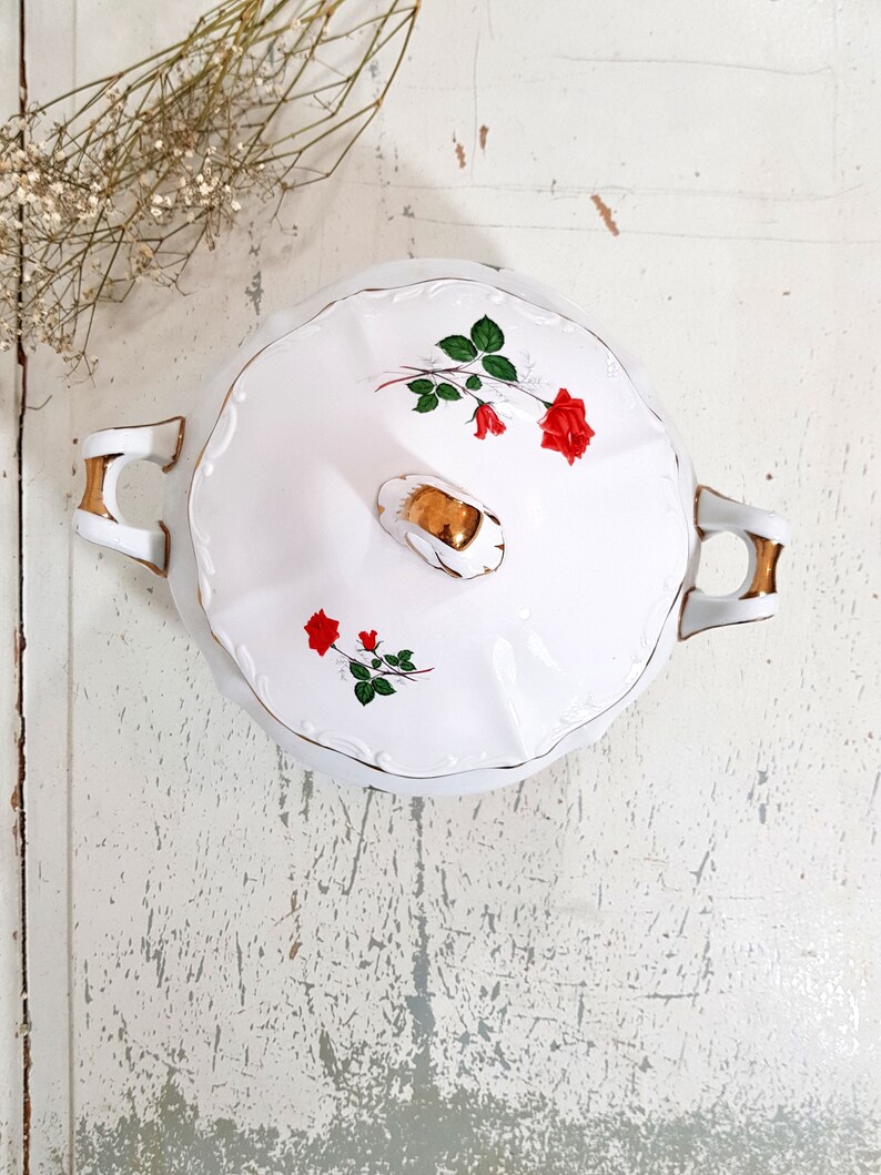 May include: White porcelain serving dish with a gold trim and a floral design featuring red roses and green leaves.