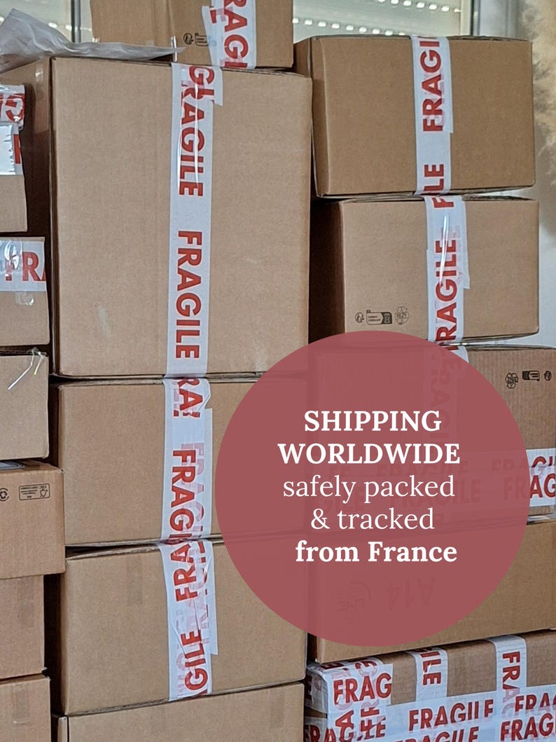Peut inclure: Plusieurs bo&icirc;tes en carton marron empil&eacute;es, scell&eacute;es avec du ruban adh&eacute;sif blanc portant l'inscription "FRAGILE" en rouge. L'image contient le texte "SHIPPING WORLDWIDE safely packed & tracked from France."