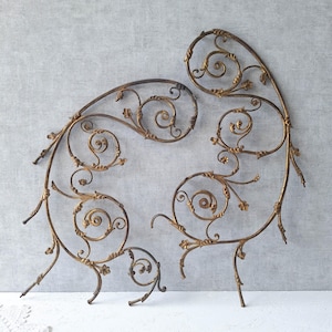 May include: Two decorative metal scrollwork pieces in an antique style. The pieces are a warm gold colour with dark brown accents, featuring floral and spiral designs. They are likely decorative elements for home decor.