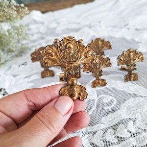 Può includere: Pomelli per cassetti antichi in ottone dorato con un elaborato motivo floreale. I pomelli hanno un'estetica decorativa e vintage, perfetta per aggiungere un tocco di eleganza ai mobili. Ogni pomello misura circa 10 cm di lunghezza.