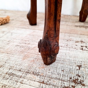 Peut inclure: Gros plan sur un pied de meuble en bois sculpt&eacute;. Le pied est brun fonc&eacute; avec des d&eacute;tails complexes et un pied d&eacute;coratif. Le grain du bois est visible et le pied semble faire partie d'une pi&egrave;ce vintage.