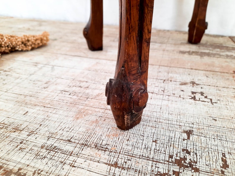 Peut inclure: Gros plan sur un pied de meuble en bois sculpt&eacute;. Le pied est brun fonc&eacute; avec des d&eacute;tails complexes et un pied d&eacute;coratif. Le grain du bois est visible et le pied semble faire partie d'une pi&egrave;ce vintage.