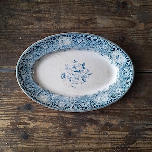 May include: An oval ceramic serving platter with a blue and white floral design. The platter has a white centre with a blue floral pattern and a blue border with a white floral pattern.