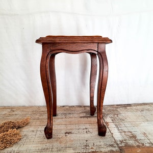 Peut inclure: Petite table d'appoint en bois antique, avec un plateau carr&eacute; et des pieds incurv&eacute;s. La table est en bois brun fonc&eacute; et pr&eacute;sente un design d&eacute;coratif. La table mesure environ 61 cm de haut.