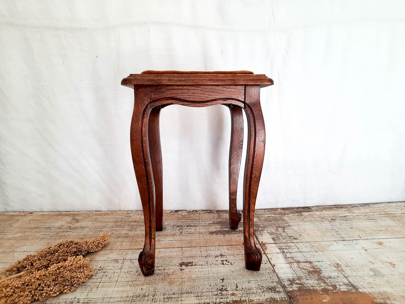 Peut inclure: Petite table d'appoint en bois antique, avec un plateau carr&eacute; et des pieds incurv&eacute;s. La table est en bois brun fonc&eacute; et pr&eacute;sente un design d&eacute;coratif. La table mesure environ 61 cm de haut.