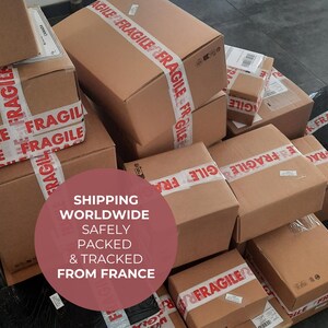 May include: A pile of various sized cardboard boxes, sealed with red and white "FRAGILE" tape. The boxes are stacked on a dark gray surface. A circular graphic states "SHIPPING WORLDWIDE SAFELY PACKED & TRACKED FROM FRANCE".