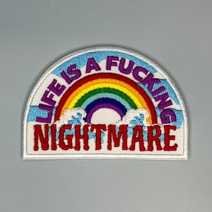 May include: White embroidered patch with a rainbow and the text "Life is a fucking nightmare".