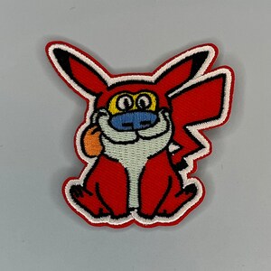 Puede incluir: Parche bordado de hierro rojo y blanco de un personaje de dibujos animados con una cara roja, amarilla y azul. El personaje tiene una barba blanca y sostiene una manzana roja en su pata derecha.