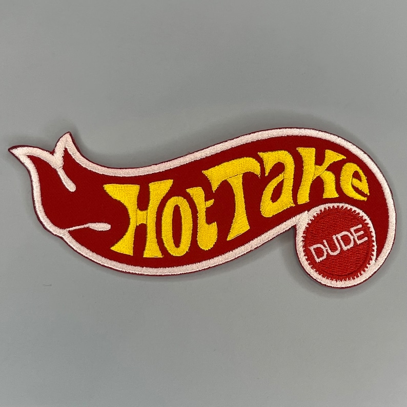May include: Red and white embroidered patch with the text "Hot Take" in yellow lettering. A smaller red circle with the word "Dude" in white lettering is on the right side of the patch.