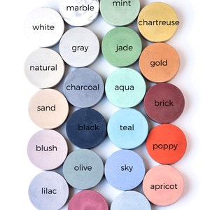 May include: A collection of 20 small round concrete coasters in various colors, including mint, marble, chartreuse, white, gray, jade, natural, gold, charcoal, aqua, brick, sand, blush, black, teal, poppy, olive, sky, apricot, lilac, plum, and ocean.