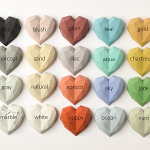 May include: Twenty geometric heart-shaped concrete paperweights in various colors, including black, blush, plum, teal, gold, charcoal, sand, lilac, aqua, chartreuse, gray, natural, apricot, sky, jade, marble, white, poppy, ocean, and mint.