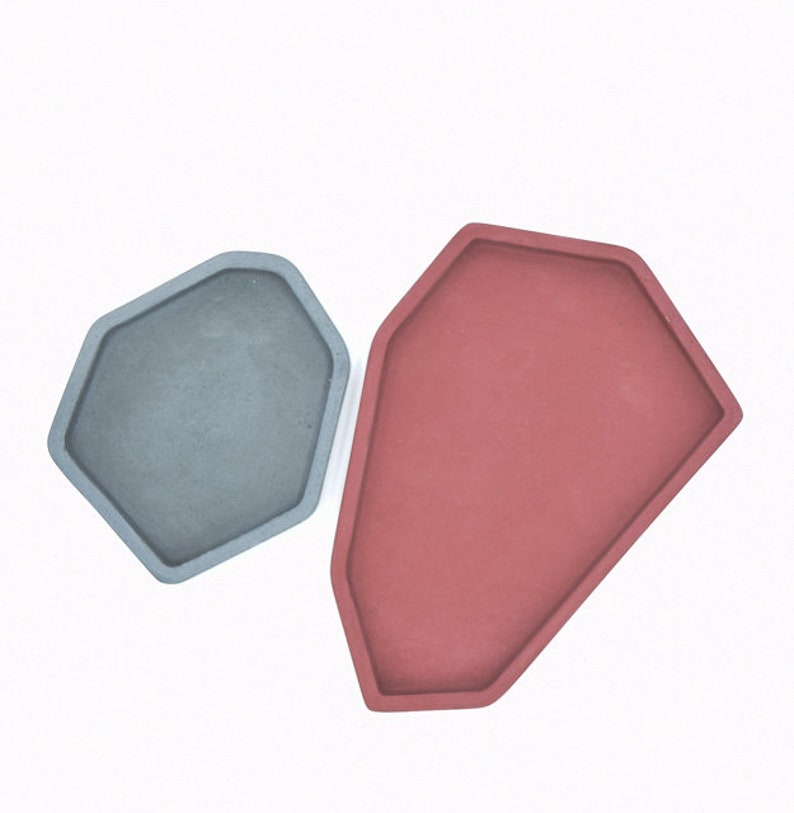 May include: Two geometric concrete trays, one gray and one red, with a slightly irregular shape.