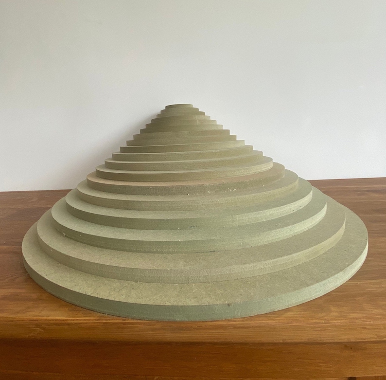 Peut inclure: Une pile de 12 disques ronds en bois vert clair, dispos&eacute;s en forme de c&ocirc;ne. Les disques sont de tailles diff&eacute;rentes, le plus grand disque &eacute;tant en bas et le plus petit en haut.