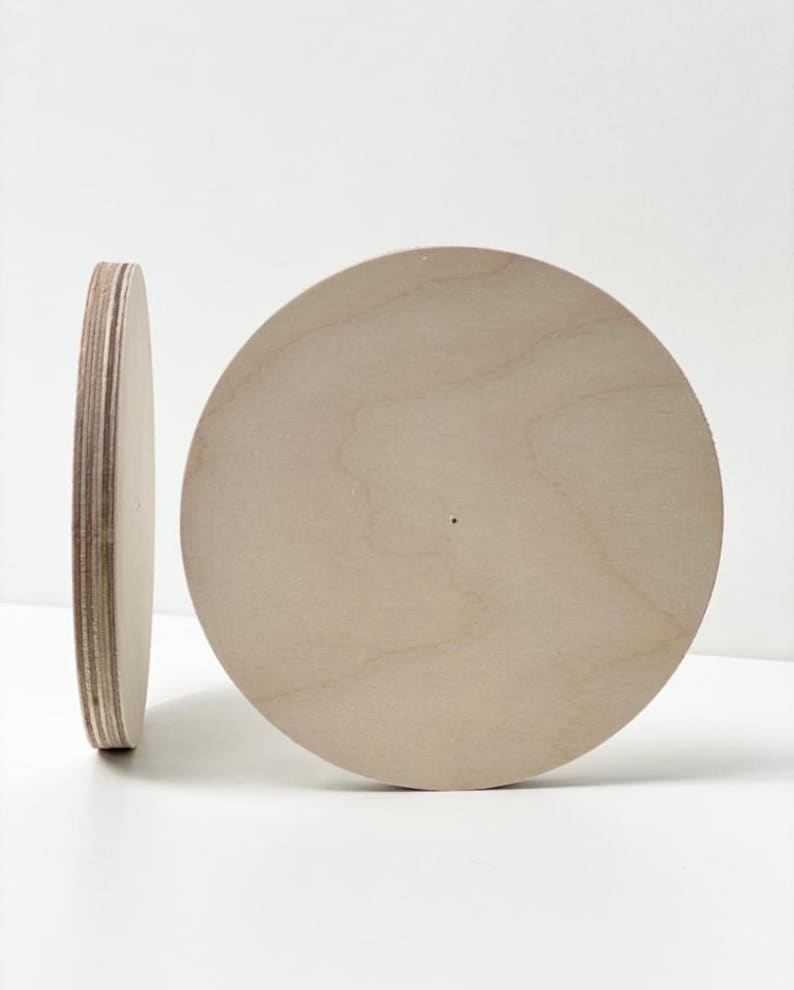 May include: Two round wooden discs, one standing upright and the other lying flat. Both discs are made of light-colored wood and have a smooth surface.