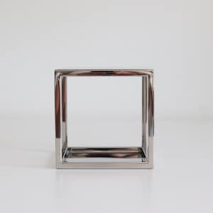Peut inclure: Une table d'appoint carrée en métal chromé au design simple et minimaliste.