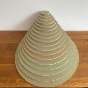 Peut inclure: Un ensemble de 18 cercles en bois de diff&eacute;rentes tailles, empil&eacute;s en forme de pyramide. Les cercles sont de couleur beige clair.