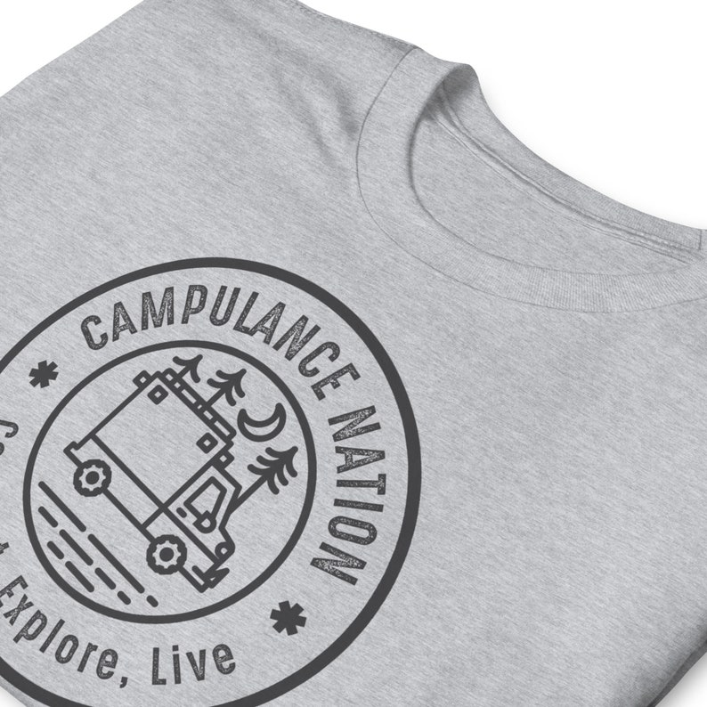 K&ouml;nnte beinhalten: Ein graues T-Shirt mit einer schwarz-wei&szlig;en Grafik eines Wohnmobils mit B&auml;umen und einer Mondsichel. Die Grafik befindet sich in einem Kreis mit dem Text "Campulance Nation" darum herum. Der Text "Explore, Live" befindet sich unter dem Kreis.