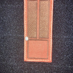 May include: A brown wooden door with a single pane of glass in the top half and a solid panel in the bottom half. The door has a white doorknob and is framed in a light brown wood.