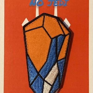 以下が含まれることがあります： オレンジと青の幾何学模様の刺繍パッチ。青色の文字で「I AM NO JEDI」と書かれています。パッチは赤い背景に白いアクセントがあり、「Nupp FX Patches」の文字があります。