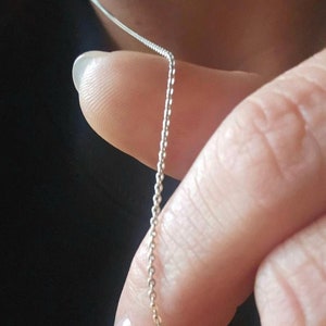May include: A silver chain necklace with a delicate, fine link design.