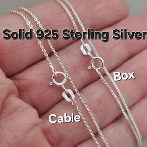 May include: Two silver chains, one cable chain and one box chain, on a hand. The chains are labeled "Cable" and "Box". The text "Solid 925 Sterling Silver" is at the top of the image.