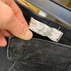 Pu&ograve; includere: Jeans in denim nero con un'etichetta bianca che recita "We The Free Twenty Eight" e "Made in Turkey / Fabrique en Turquie".