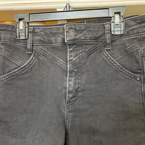 Pu&ograve; includere: Jeans in denim nero a vita alta e gamba dritta. I jeans hanno una chiusura con bottoni e passanti per la cintura.