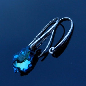May include: A pair of silver dangle earrings with a blue crystal teardrop pendant.