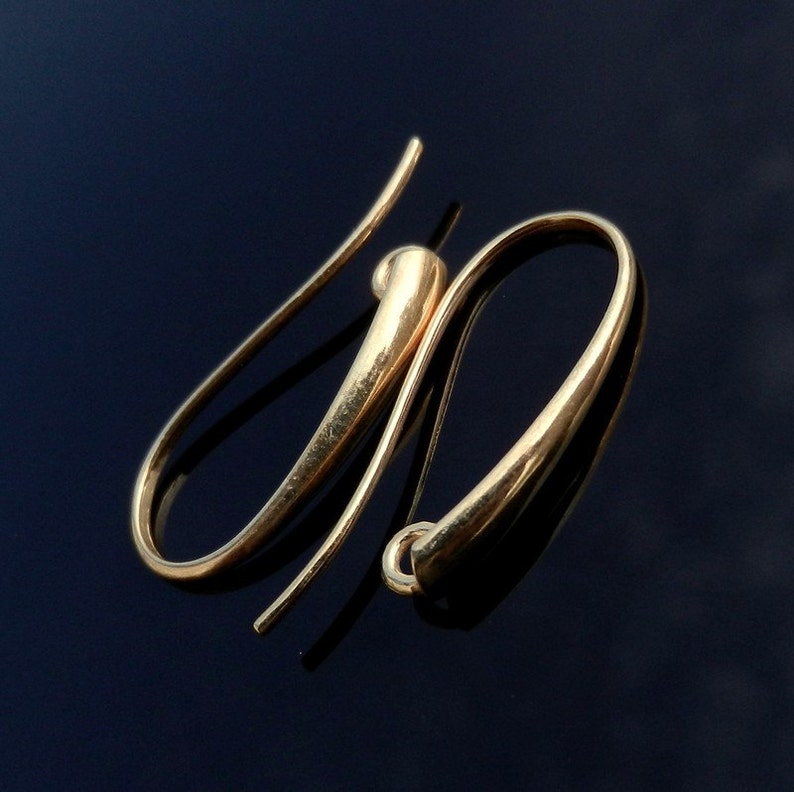 May include: A pair of gold-toned earring hooks. The hooks are made of a smooth, rounded metal and have a simple, elegant design.