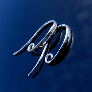 May include: Two silver earring hooks with a curved design. The hooks are made of metal and have a shiny finish.