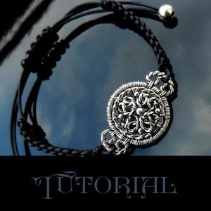 Op de afbeelding: Een zilveren armband met een ronde, ingewikkelde draadgewikkelde hanger. De armband is gemaakt van zwart lederen koord en heeft een zilveren schuifgesp.