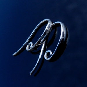 May include: A pair of silver hoop earrings with a unique curved design. The earrings are smooth and shiny, and they have a modern and stylish look.