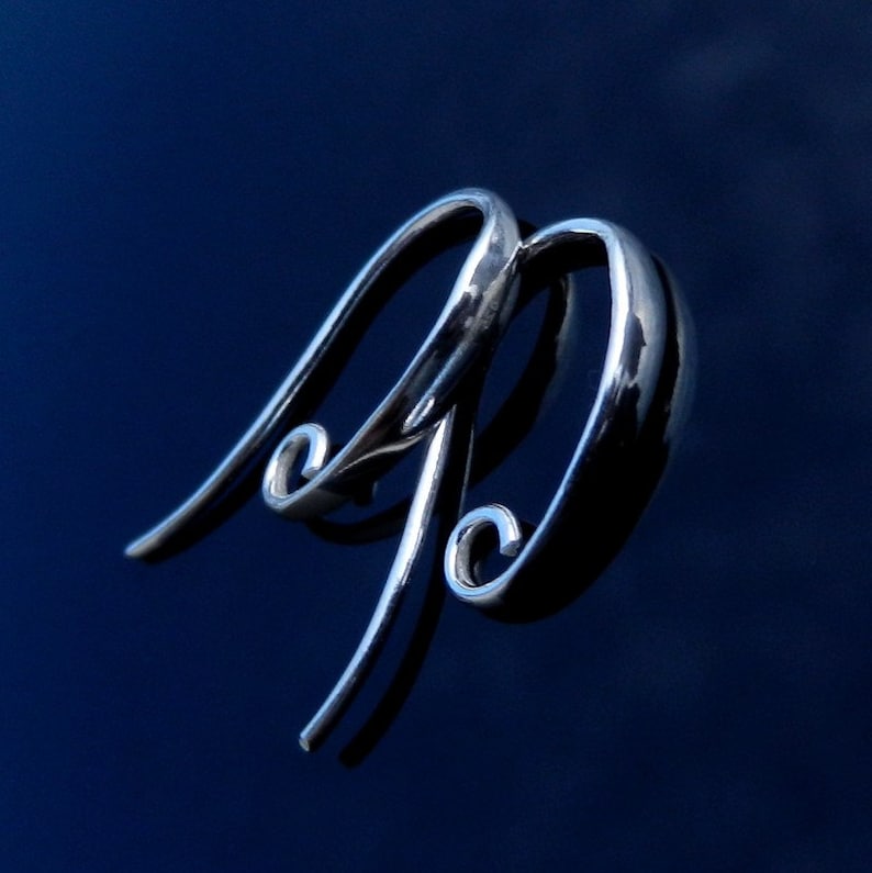 May include: A pair of silver hoop earrings with a unique curved design. The earrings are smooth and shiny, and they have a modern and stylish look.