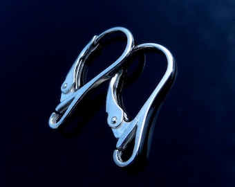 May include: Two silver earring clips, a type of jewelry finding, are shown against a dark blue background. The clips are made of metal and have a smooth, polished finish.