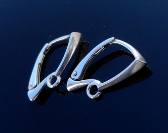 May include: A pair of silver-colored hoop earrings. Each earring has a curved, rectangular design with a hinged closure. The earrings are displayed on a reflective, dark blue surface.