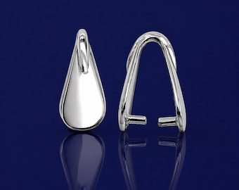 Puede incluir: Dos piezas de joyería plateadas. Una tiene forma de lágrima con un lazo en la parte superior. La otra es un diseño curvo en forma de arco con dos pequeños postes en la base. Ambas piezas tienen una superficie brillante y reflectante.