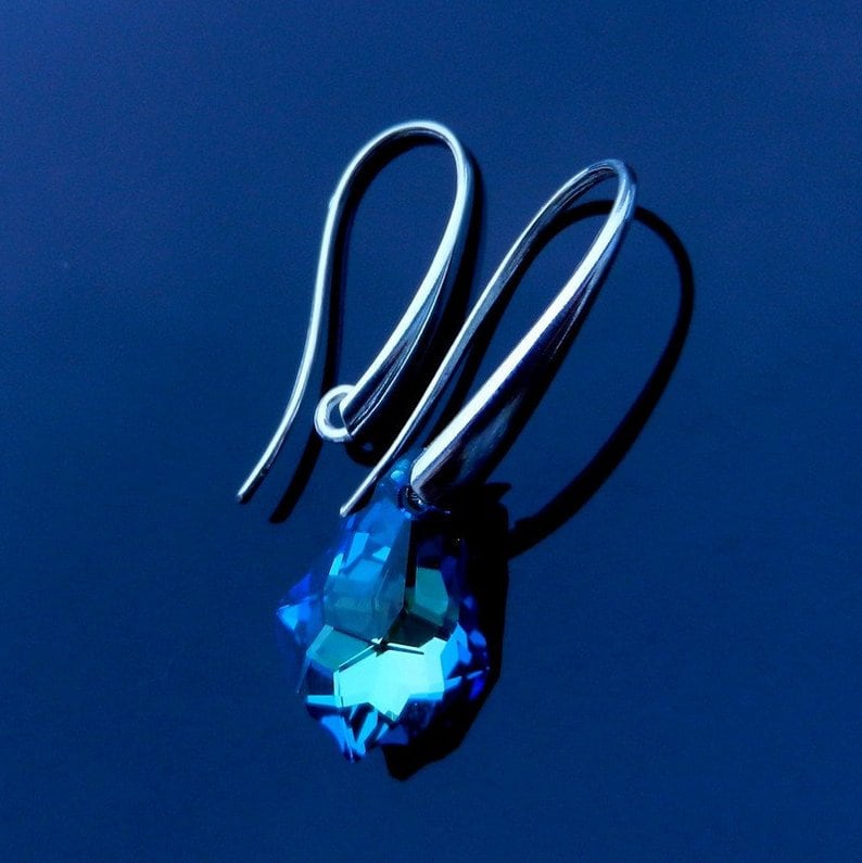 May include: A pair of silver dangle earrings with a blue crystal teardrop pendant.