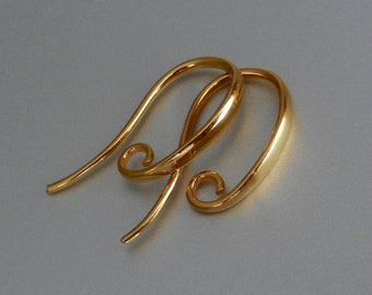 May include: A pair of gold-toned earring hooks with a curved design. The hooks are made of metal and have a smooth finish.