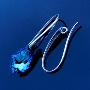 May include: Silver dangle earrings with a blue crystal teardrop pendant.