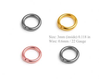 May include: Four metal jump rings in different colors: dark gray, gold, rose gold, and a lighter gray. The text on the image indicates the size is 3mm inside diameter, with a 0.6mm wire, equivalent to 22 gauge.