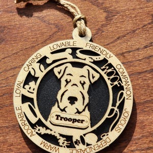 May include: A wooden ornament shaped like a dog with the name "Trooper" on a tag. The ornament is decorated with words describing a dog's personality, such as "Loyal", "Caring", "Friendly", and "Dependable".