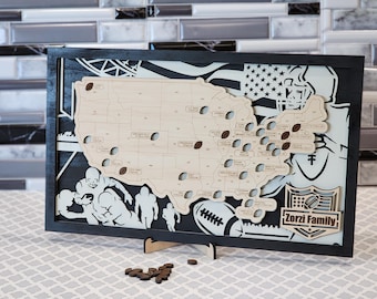 May include: A wooden map of the United States with football-shaped cutouts and football details. The map is framed in black and features football-themed graphics and the text "Zorzi Family". Includes small wooden footballs.