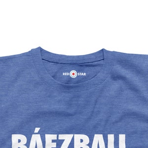 May include: A royal blue t-shirt with the text "B&Aacute;EZBALL" in white letters. The shirt has a red star logo with the text "RED STAR" on the neck.