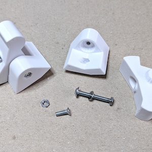 Puede incluir: Cuatro piezas de pl&aacute;stico blanco impresas en 3D para un mecanismo de bisagra, junto con dos tornillos plateados y dos tuercas plateadas.