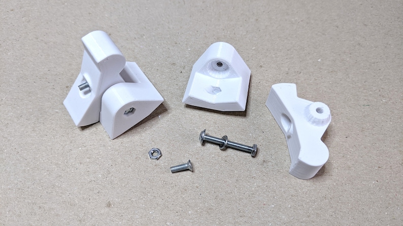 Puede incluir: Cuatro piezas de pl&aacute;stico blanco impresas en 3D para un mecanismo de bisagra, junto con dos tornillos plateados y dos tuercas plateadas.