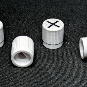 May include: Four white plastic knobs with different symbols on top. The symbols are a triangle, an X, a circle, and a square.