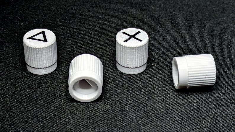 May include: Four white plastic knobs with different symbols on top. The symbols are a triangle, an X, a circle, and a square.