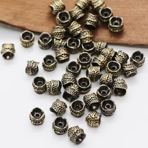 Può includere: Una collezione di perline in metallo color oro antico con una superficie testurizzata. Le perline sono rotonde e hanno un piccolo foro al centro. Sono perfette per la creazione di gioielli o altri progetti di artigianato.