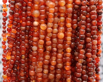 May include: A strand of carnelian beads, featuring a deep orange color with a smooth, rounded shape. The beads are strung together on a clear thread, creating a continuous strand.